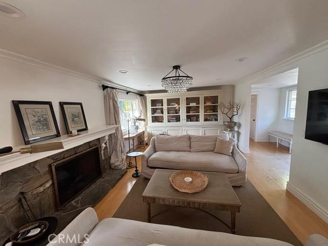 living room with a fireplace, ornamental molding, and wood-type flooring