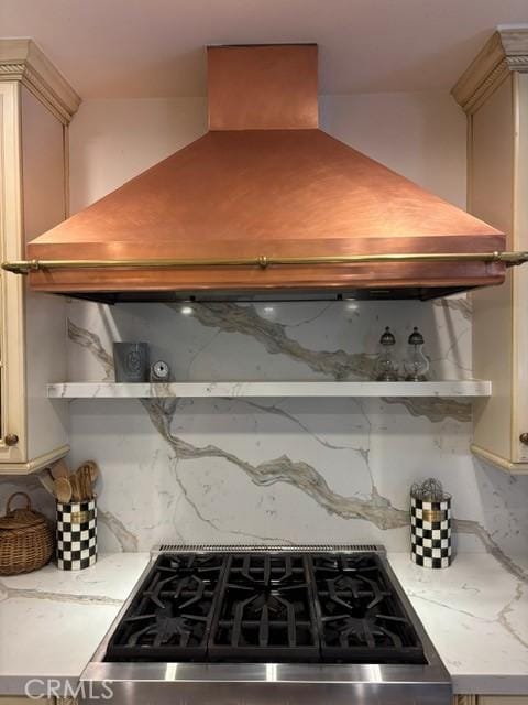 kitchen featuring tasteful backsplash, cream cabinets, stainless steel range oven, and premium range hood