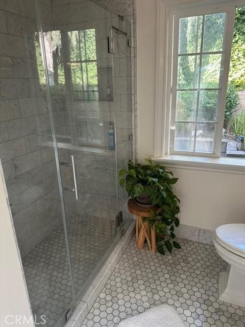 bathroom with a shower with shower door, tile patterned floors, and toilet