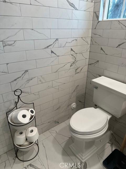 bathroom with tile walls and toilet