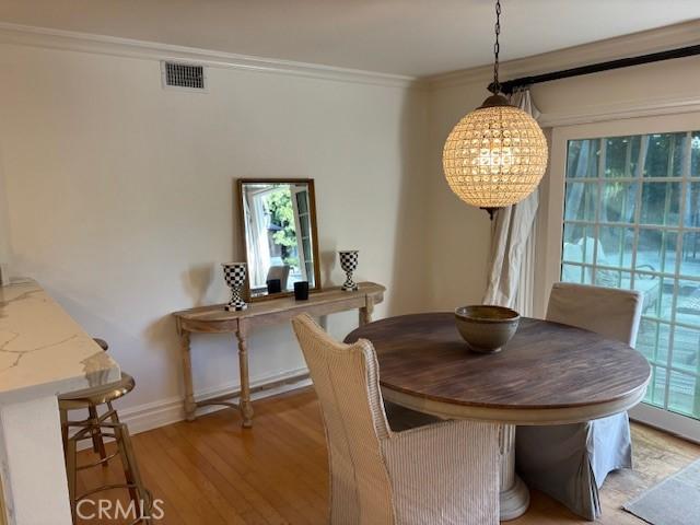 dining area featuring ornamental molding, a chandelier, and light hardwood / wood-style flooring