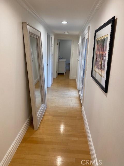 hallway with ornamental molding and light wood-type flooring