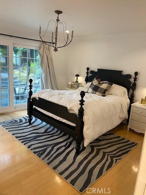 bedroom with crown molding, wood-type flooring, and a chandelier