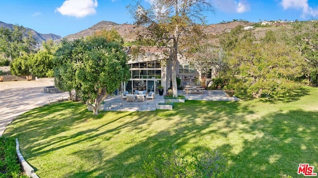 rear view of house featuring a mountain view, a lawn, a patio, and an outdoor hangout area