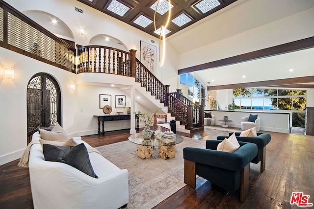 living room featuring dark hardwood / wood-style floors, beam ceiling, and a high ceiling