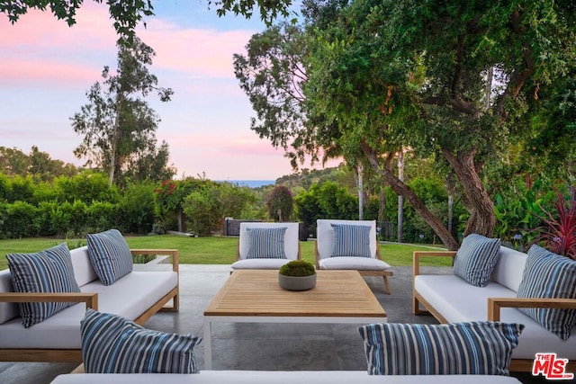 patio terrace at dusk with an outdoor hangout area and a lawn