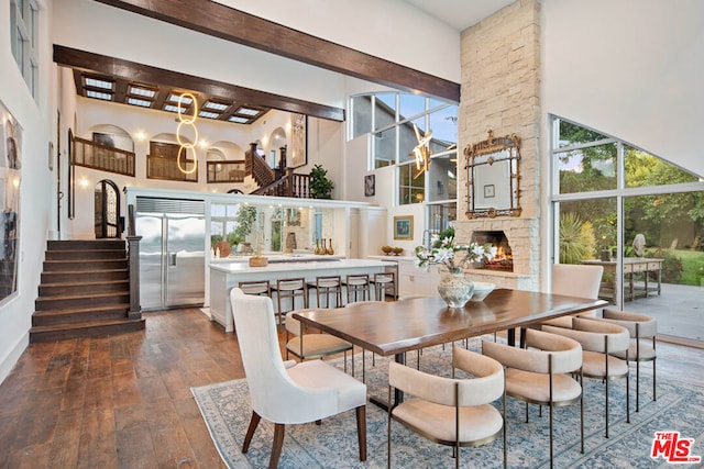 dining room featuring a stone fireplace, a towering ceiling, and dark hardwood / wood-style floors