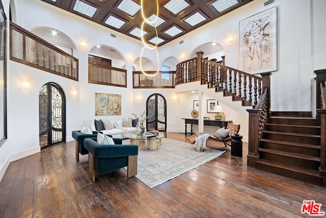 living room featuring coffered ceiling, dark hardwood / wood-style floors, and a high ceiling