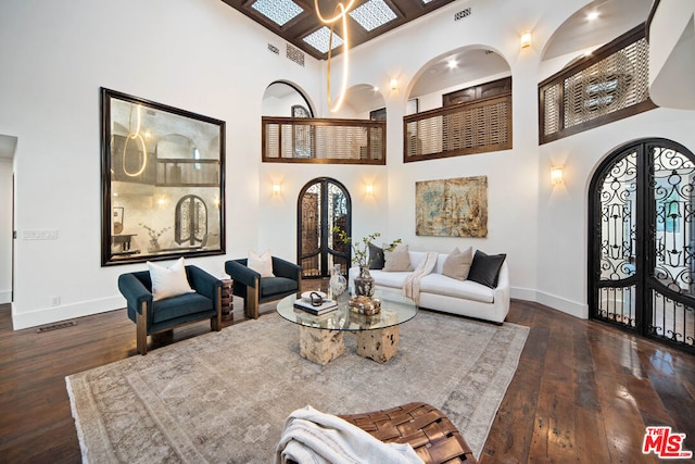 living room featuring dark wood-type flooring, french doors, and a high ceiling