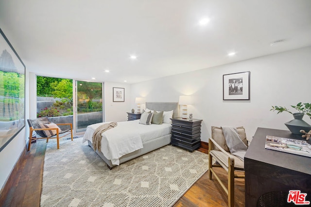 bedroom with hardwood / wood-style flooring, access to outside, and expansive windows