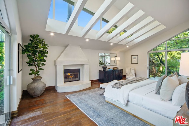 bedroom featuring dark hardwood / wood-style flooring, a skylight, and high vaulted ceiling