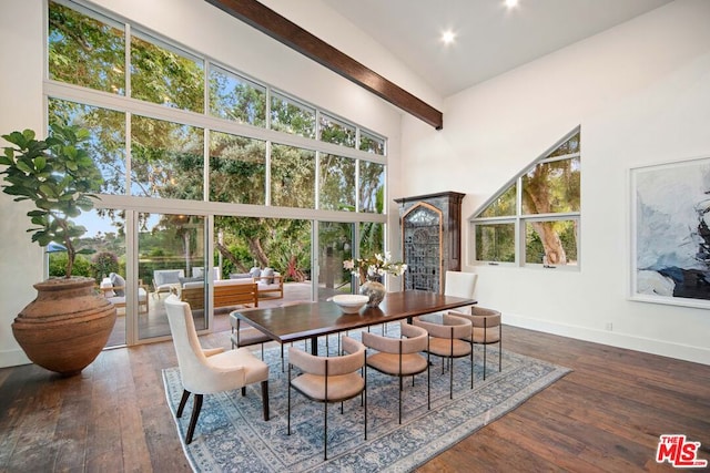 dining space featuring a towering ceiling, dark wood-type flooring, and plenty of natural light