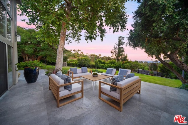 patio terrace at dusk with an outdoor living space and a yard