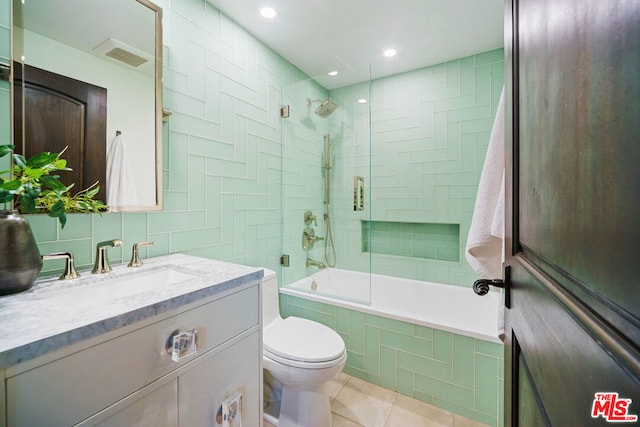 full bathroom with toilet, tiled shower / bath, tile walls, vanity, and tile patterned flooring