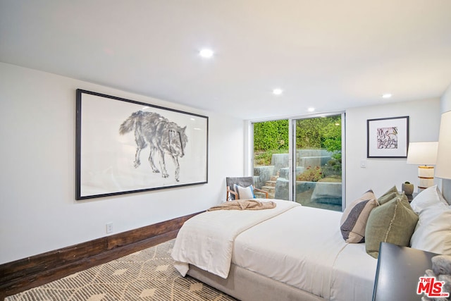 bedroom featuring wood-type flooring, access to exterior, and a wall of windows