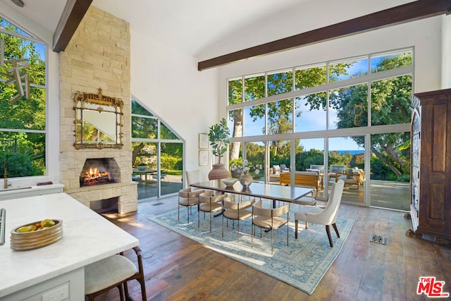 dining room with high vaulted ceiling, a fireplace, and hardwood / wood-style floors