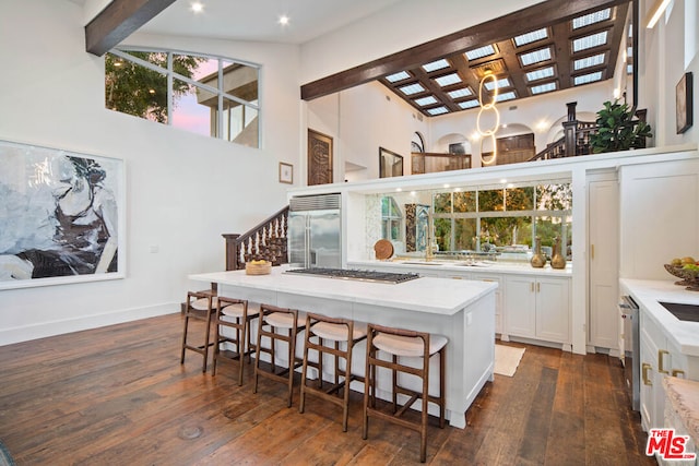 kitchen with a breakfast bar, white cabinetry, appliances with stainless steel finishes, dark hardwood / wood-style flooring, and a kitchen island