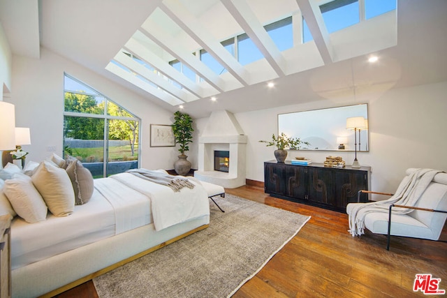 bedroom with wood-type flooring, a fireplace, and vaulted ceiling with skylight