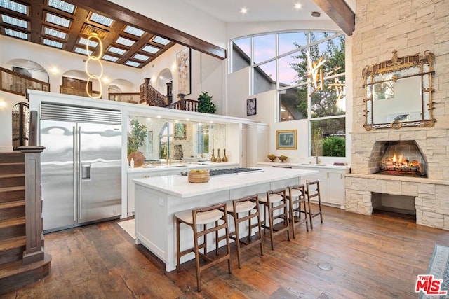 kitchen featuring white cabinetry, dark hardwood / wood-style flooring, a high ceiling, a center island, and stainless steel appliances