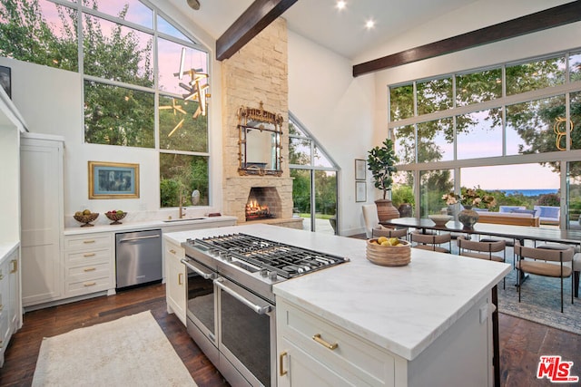 kitchen featuring dark wood-type flooring, appliances with stainless steel finishes, a center island, a fireplace, and white cabinets