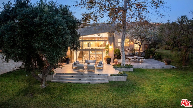 rear view of house with a patio, a balcony, an outdoor hangout area, and a lawn