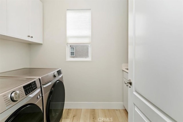 laundry area with cabinets, light hardwood / wood-style floors, and washer and dryer