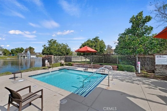 view of pool featuring a patio area and a water view