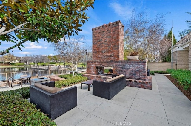 view of patio with an outdoor living space with a fireplace and a water view