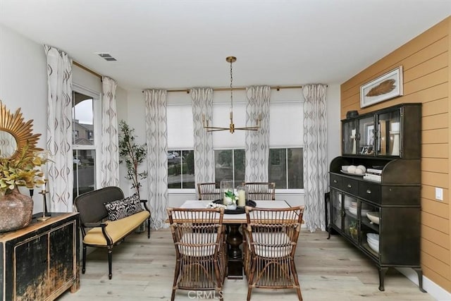 dining room with light hardwood / wood-style floors and wood walls