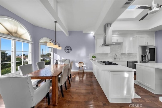 kitchen with stainless steel appliances, white cabinetry, island range hood, and decorative light fixtures