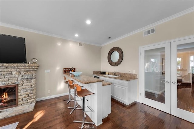 bar featuring dark wood-type flooring, french doors, white cabinetry, light stone counters, and ornamental molding