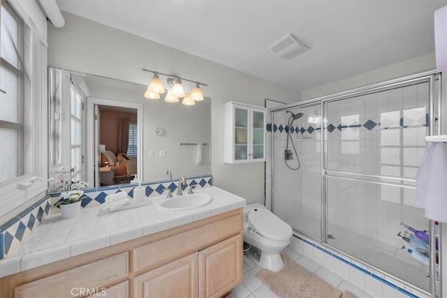 bathroom featuring tile patterned flooring, vanity, an enclosed shower, and toilet