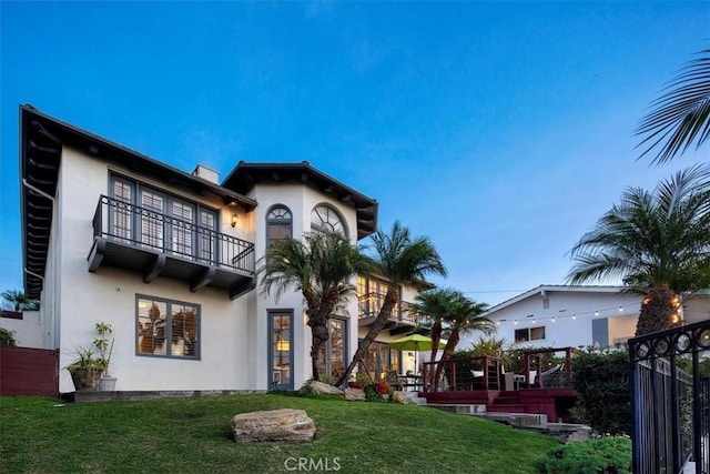 view of front facade featuring a balcony, a front yard, and a pergola