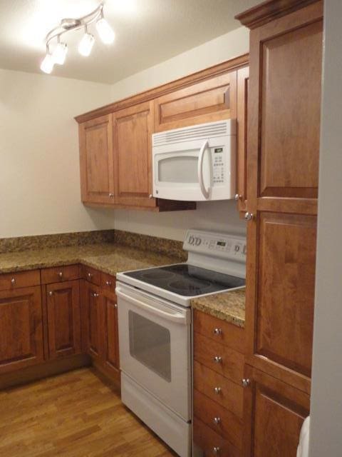 kitchen featuring white appliances, stone countertops, and light hardwood / wood-style floors