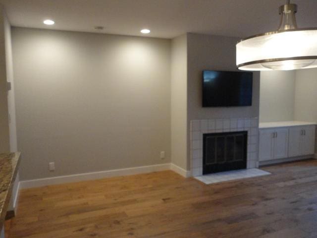 unfurnished living room featuring hardwood / wood-style floors and a tile fireplace