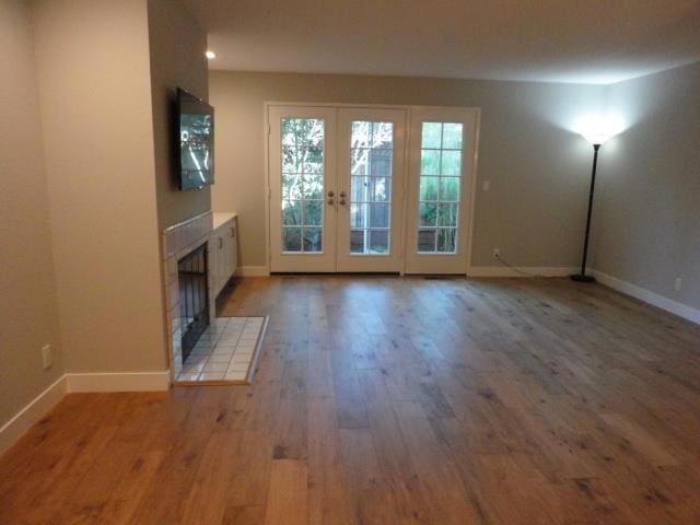 unfurnished living room with french doors, wood-type flooring, and a fireplace