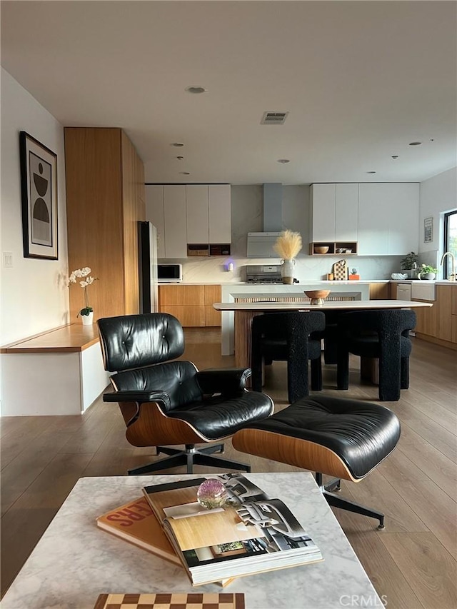 kitchen featuring stainless steel appliances, white cabinets, a kitchen bar, and light hardwood / wood-style flooring