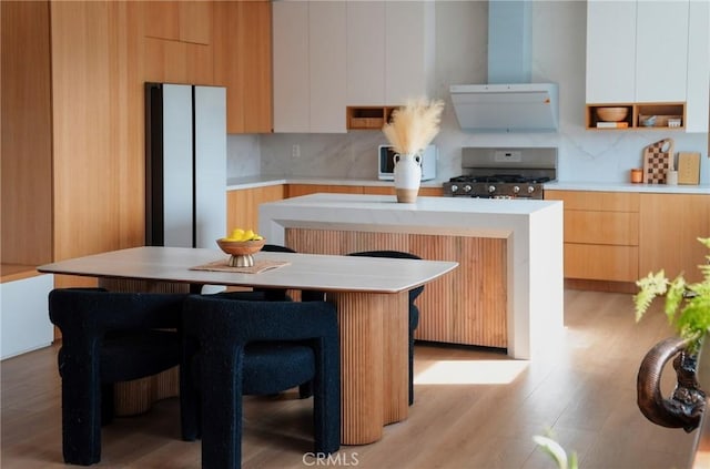 kitchen featuring stainless steel stove, exhaust hood, white cabinets, and a center island