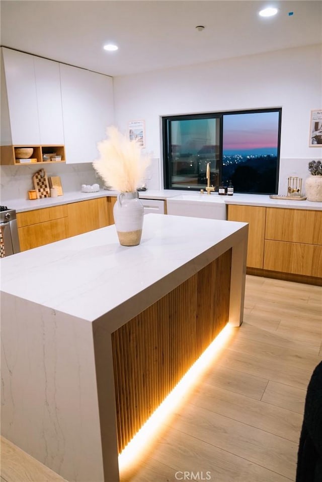 kitchen featuring sink, light hardwood / wood-style flooring, white cabinets, and a kitchen island