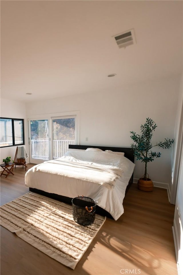 bedroom with wood-type flooring and access to exterior