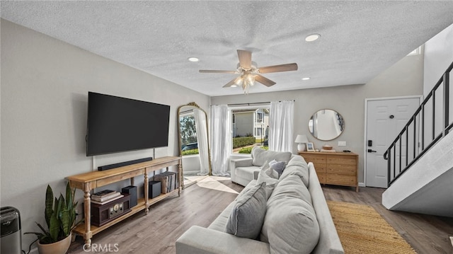 living room featuring hardwood / wood-style flooring, ceiling fan, and a textured ceiling