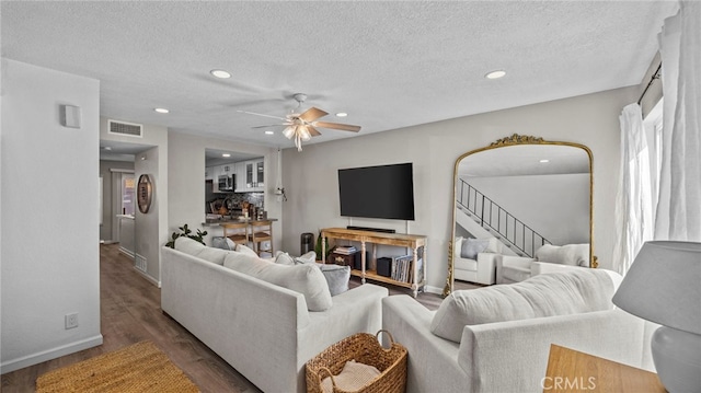 living room featuring dark wood-type flooring, ceiling fan, and a textured ceiling