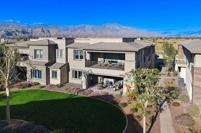 back of property featuring a mountain view, central AC unit, a lawn, and a balcony