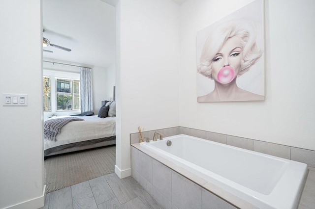 bathroom with tiled tub, hardwood / wood-style floors, and ceiling fan