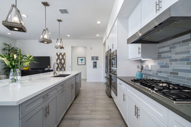 kitchen with extractor fan, dark stone counters, pendant lighting, stainless steel appliances, and white cabinets