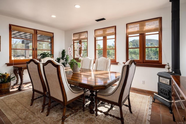 dining space featuring dark tile patterned floors and a wood stove