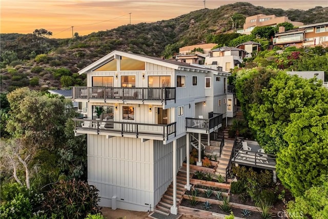 22332 Eagle Rock Way, Laguna Beach, CA 92651 - back of property at dusk featuring a balcony, stairs, a mountain view, and board and batten siding