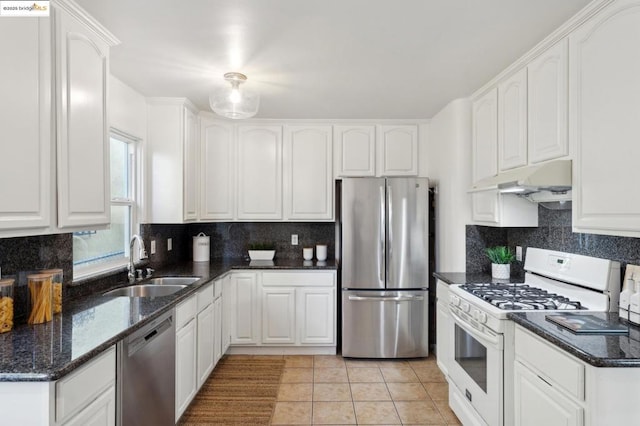 kitchen featuring sink, white cabinetry, dark stone countertops, stainless steel appliances, and decorative backsplash