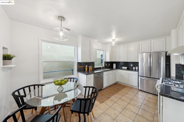 kitchen featuring sink, light tile patterned floors, appliances with stainless steel finishes, white cabinetry, and decorative backsplash