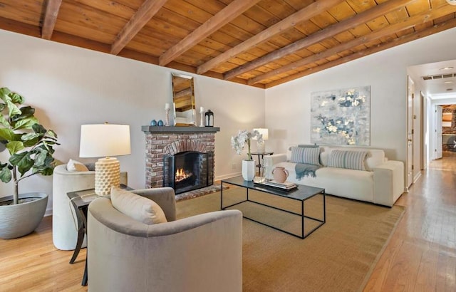 living room featuring a fireplace, wood ceiling, light hardwood / wood-style flooring, and lofted ceiling with beams